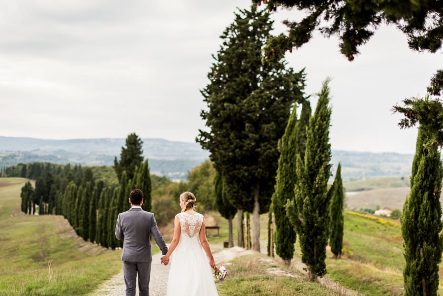 bride groom walking tuscany cypresses