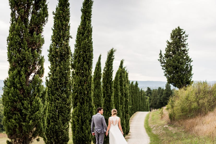 bride groom walking street tuscany cypresses