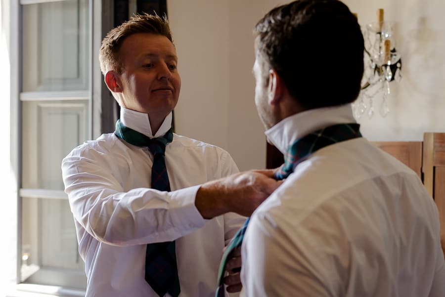 Bestman helping the groom with his necktie