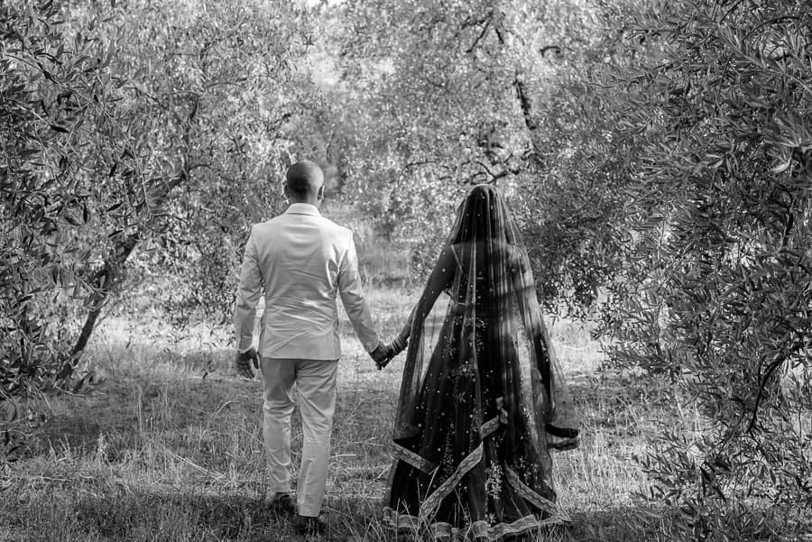 Bride and groom walking thru the olive trees in tuscany black and white