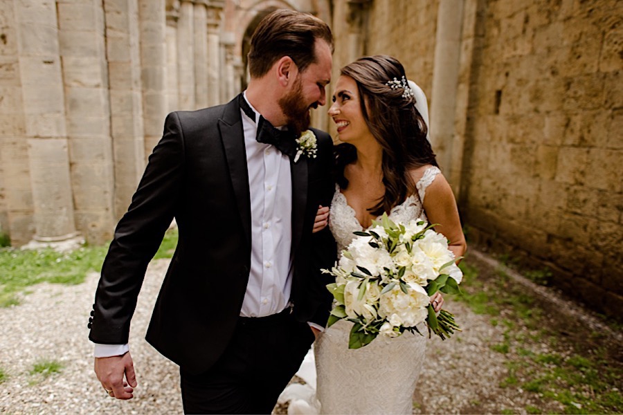 Bride and groom wlaking and smiling together at san galgano abbey