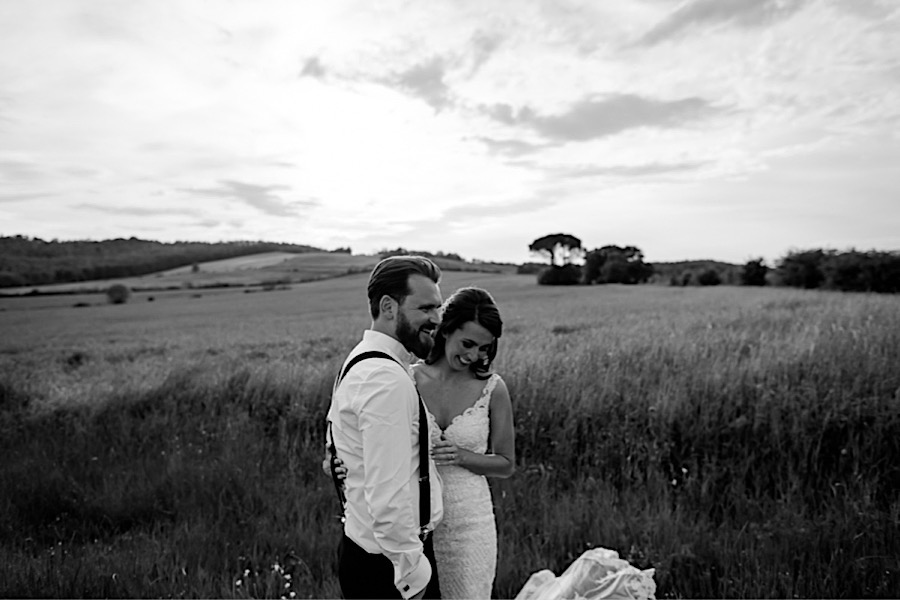 Bride and groom smiling on the tuscany countryside black and white photo