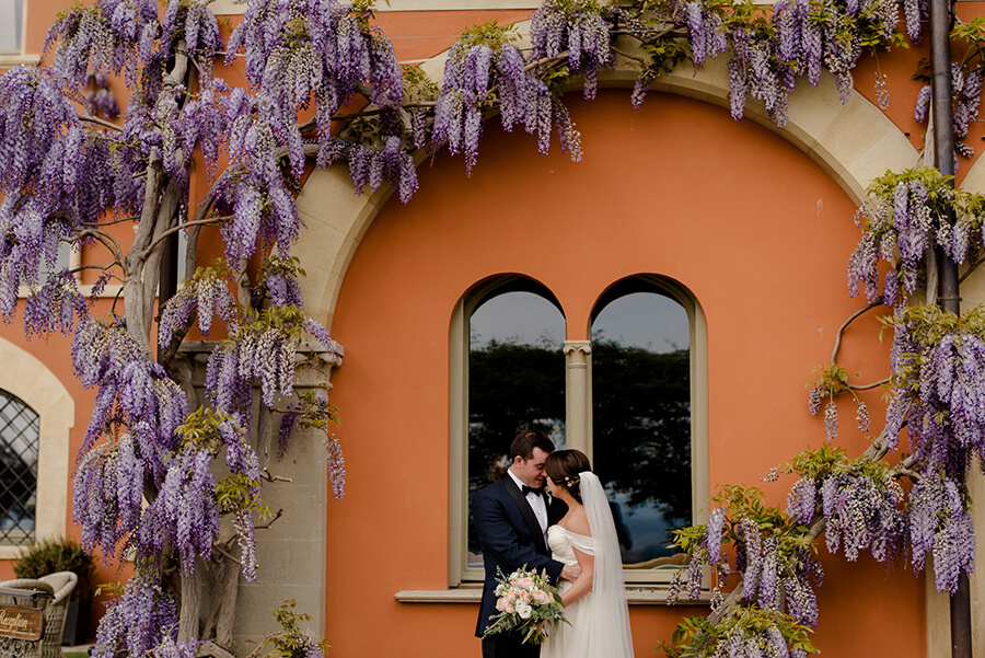 Bride and Groom portrait ahead to the window and with wisteria