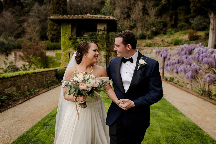 newlywed couple walking and smilign together in tuscany