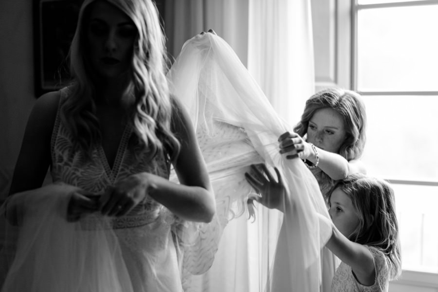 little bridesmaids helping the bride with the wedding dress black and white photo