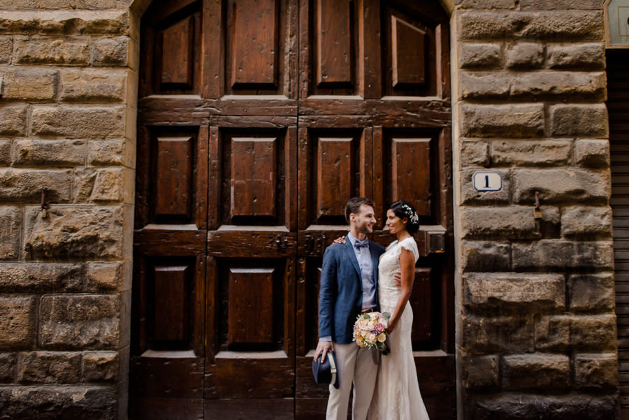 bride and groom in front of ancient big brown door in florence