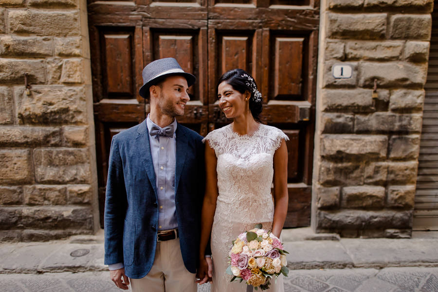 bride and groom in front of ancient big brown door in florence and smiling