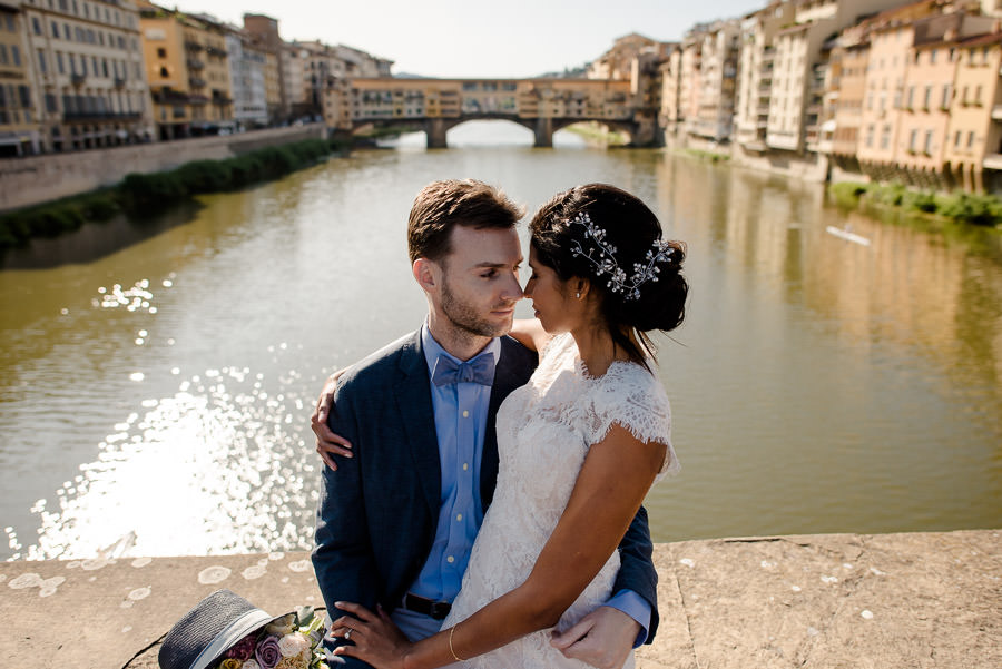 bride and groom at ponte santa trinita with ponte vecchio as backdrop
