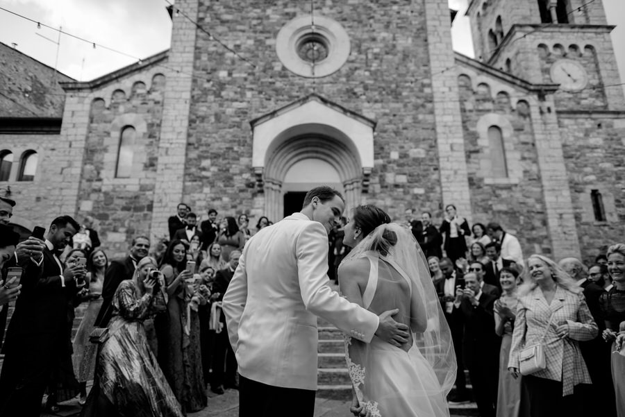 kiss of bride and groom in front of the church black and white