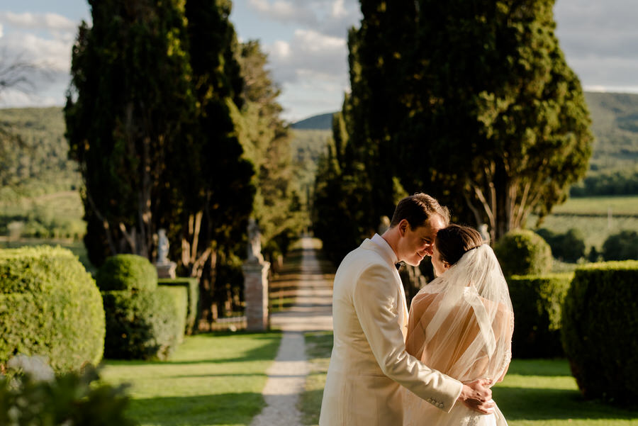 bride and groom kissing with the tuscan cypress road in the background