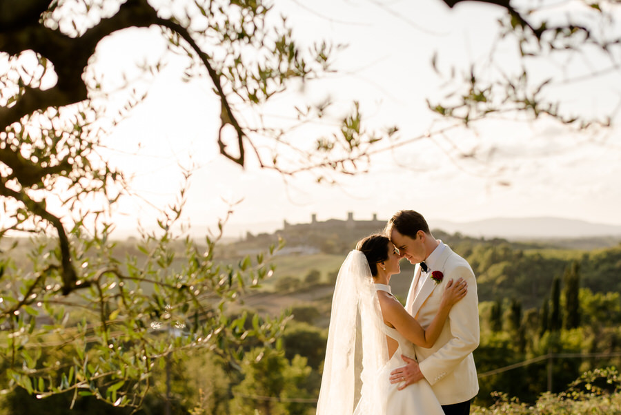 bride and groom intimate moment at borgo stomennano with monteriggioni in the background