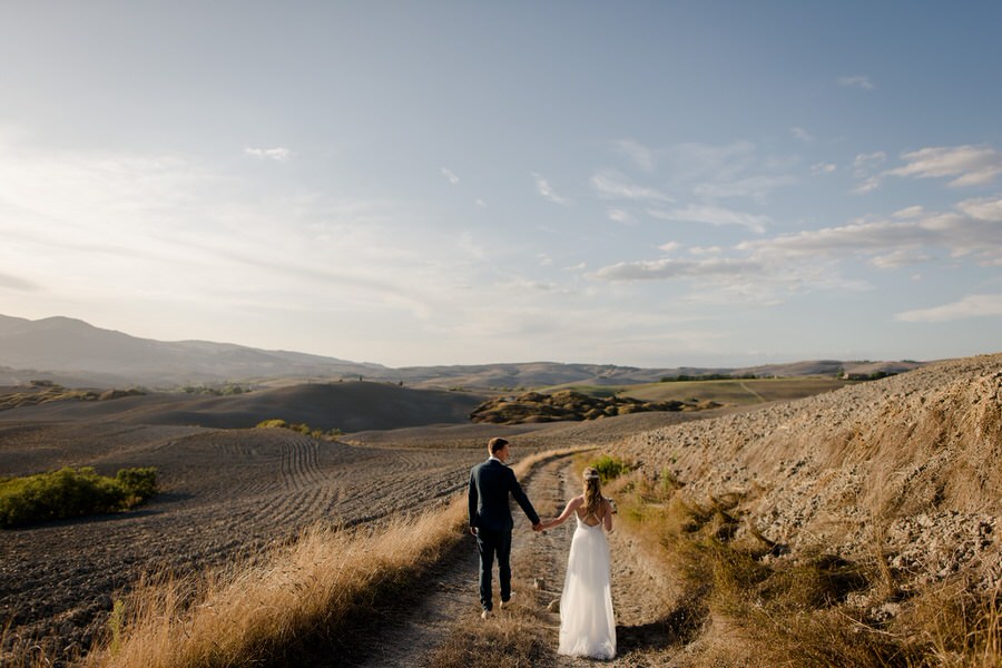 wedding couple walking in the tuscan hills.