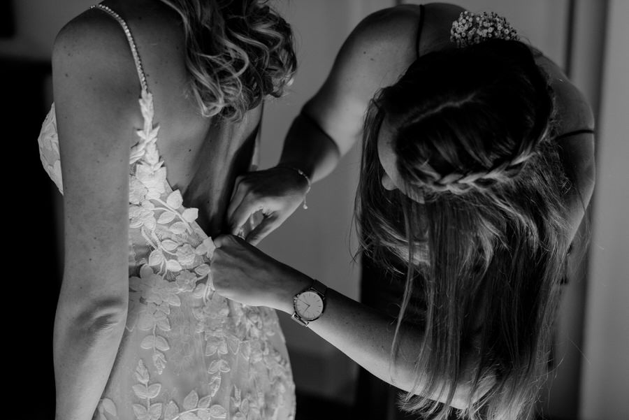 bridesmaid helping the bride to wear the wedding dress