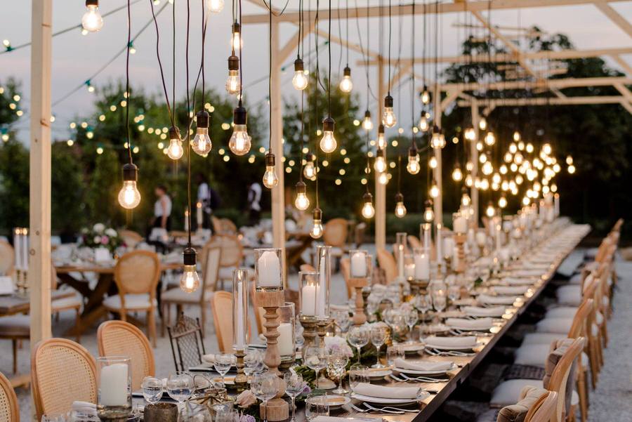 wedding dinner with a long table decorated with candles and bulb lights