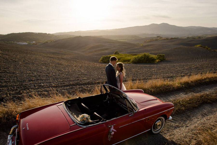 wedding couple in tuscany with a vintage red car