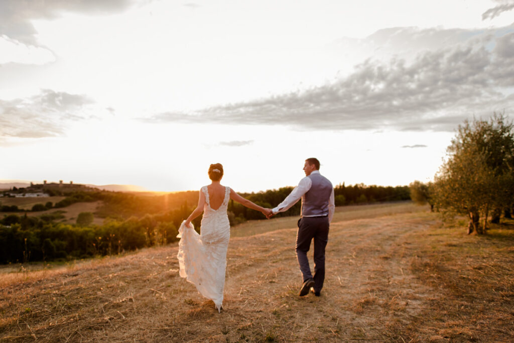 newlywed couple walking together in the sunset of tuscany landscape